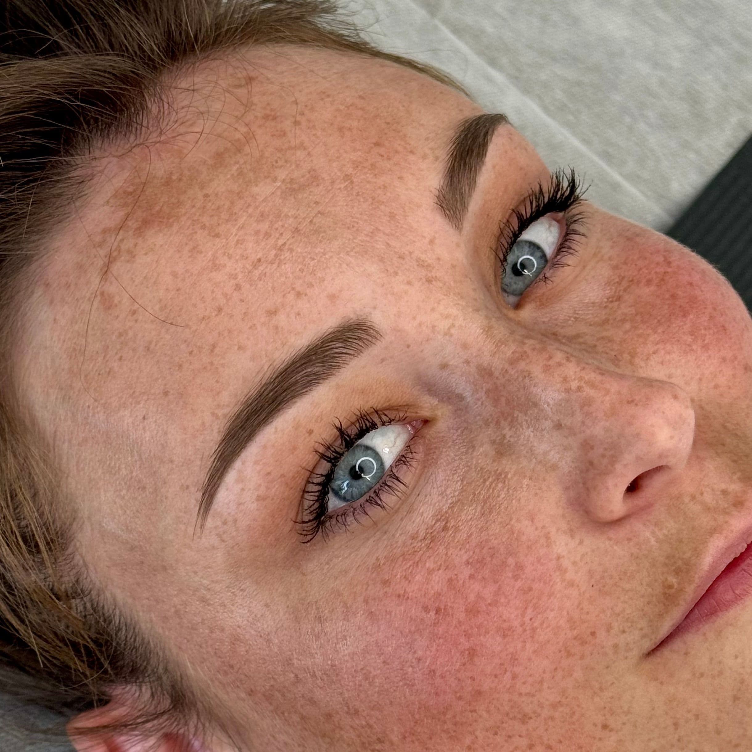 Pigmentation des sourcils naturelle et semi-permanente sur une femme aux yeux bleus et taches de rousseur, par la formatrice Habiba Med.